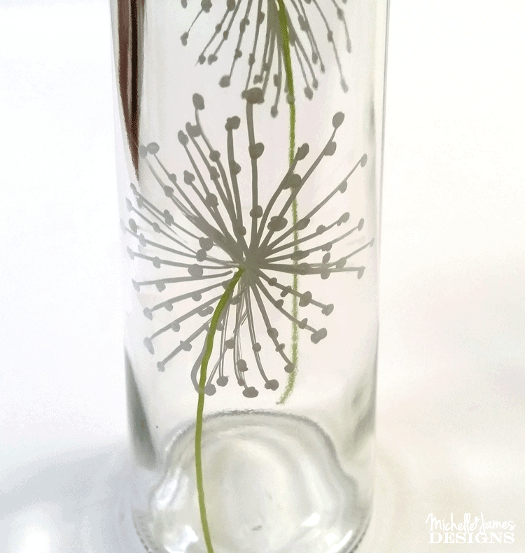 Using a paint pent to draw dandelions onto a dollar store vase to make some outdoor solar lights.