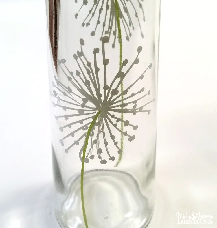Using a paint pent to draw dandelions onto a dollar store vase to make some outdoor solar lights.