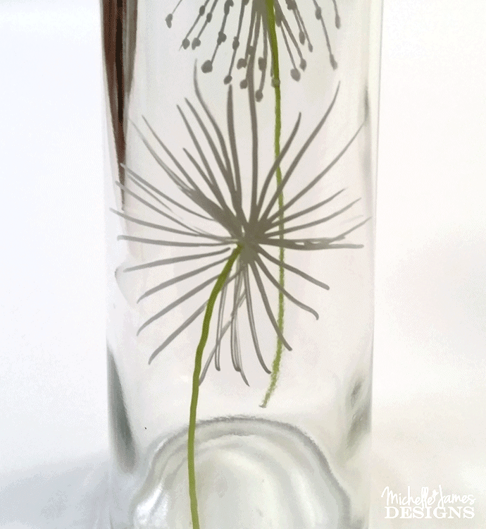 Using a paint pent to draw dandelions onto a dollar store vase to make some outdoor solar lights.