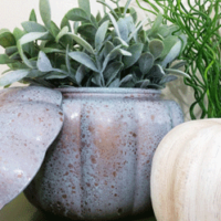 finished faux patina glass pumpkin with greenery and a painted pumpkin.