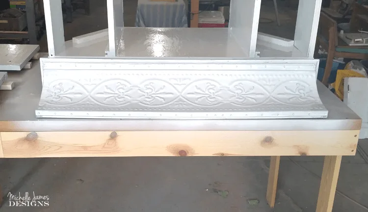 Painting the metal shelf with the white chalk paint.