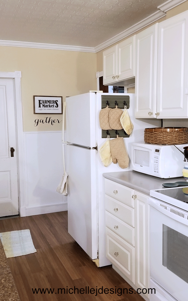 I used a piece of trim from a garage sale to create an upcycled kitchen oven mitt organizer. I love it! - www.michellejdesigns.com