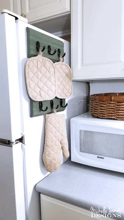 I used a piece of trim from a garage sale to create an upcycled kitchen oven mitt organizer. I love it! - www.michellejdesigns.com