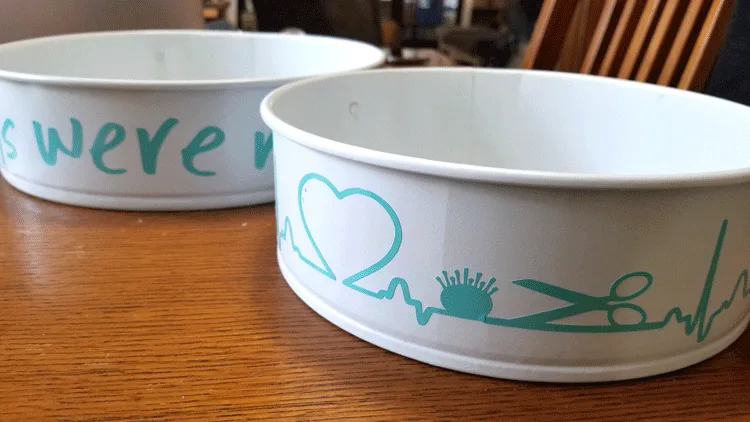 White painted pans with teal vinyl designs on the sides.