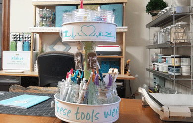 Photo of full upcyled tiered craft organizer full of tools with craft space in the background.