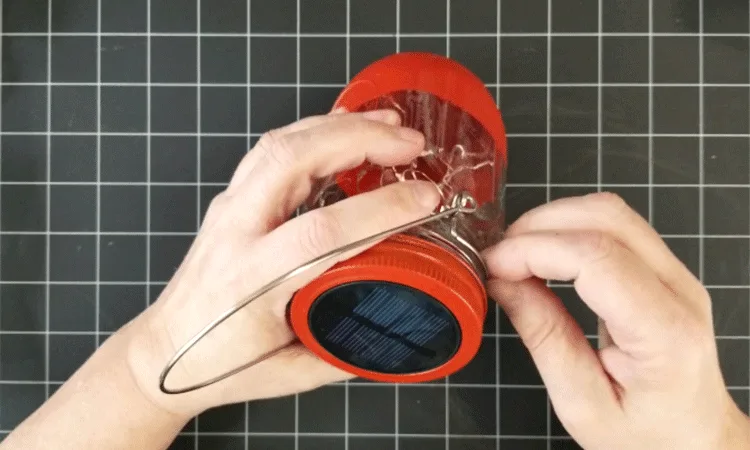 Securing the hanging wire around the rim of the mason jar light.