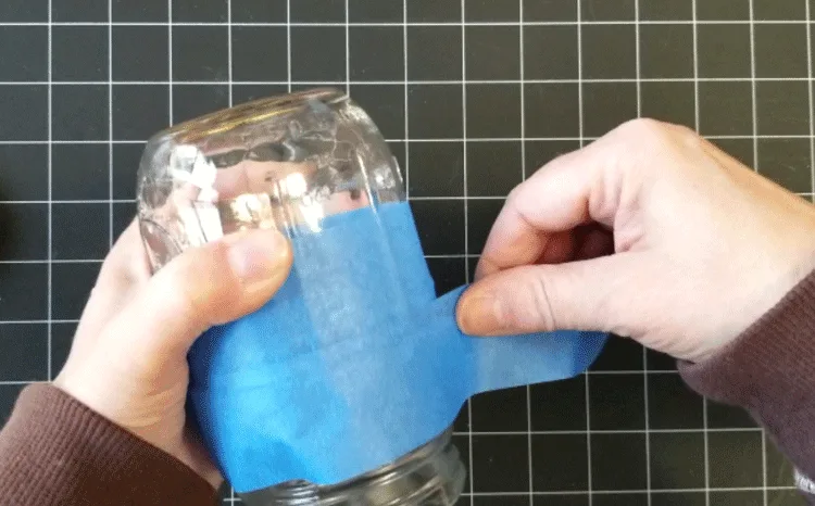 Using painters tape to mask off the area of the jar that doesn't get painted.