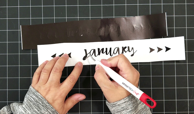 Weeding the small pieces of vinyl from the text design in preparation to attach it to the calendar piece.