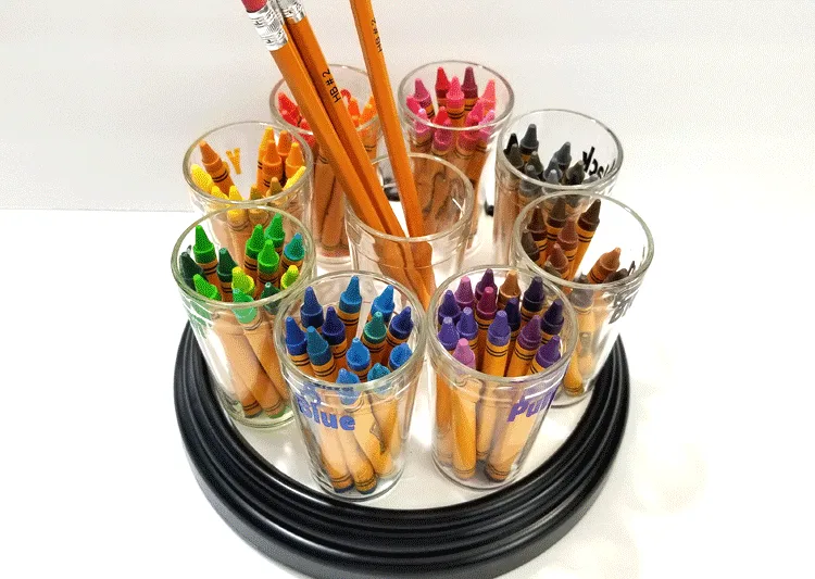 All of the colors of crayons separated into families and placed on the crayon holder carousel.