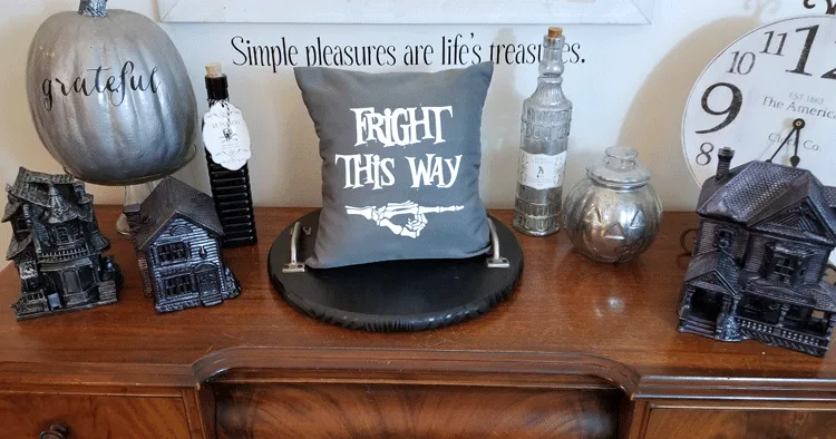Gray and white "Fright This Way" pillow staged on wood desk with haunted house village and potion bottles.