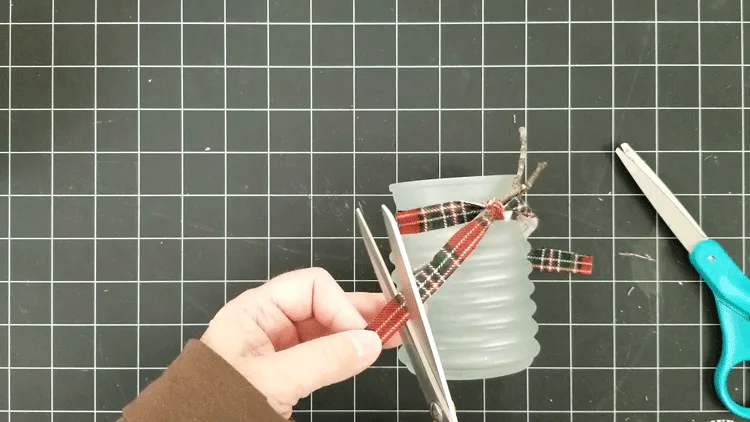 Trimming the ends of the plaid fabric ribbon to length.
