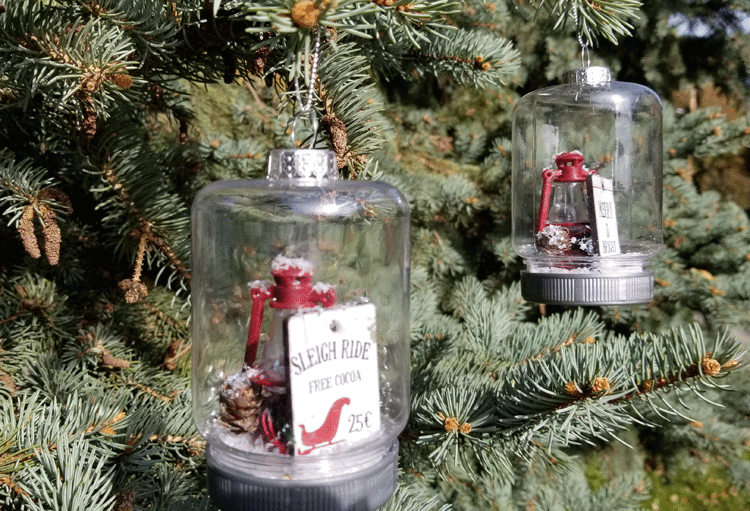 The finished mason jar ornaments all finished and hanging on a tree.