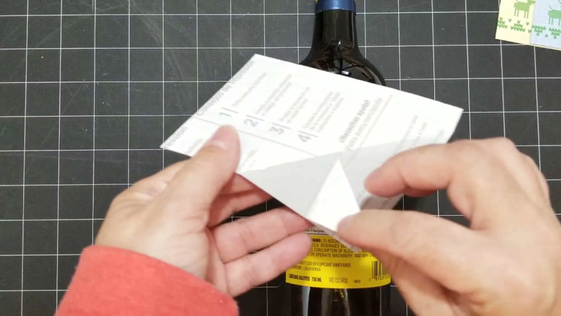 Peeling off the backing of the sticker paper to adhere the holiday wine label.