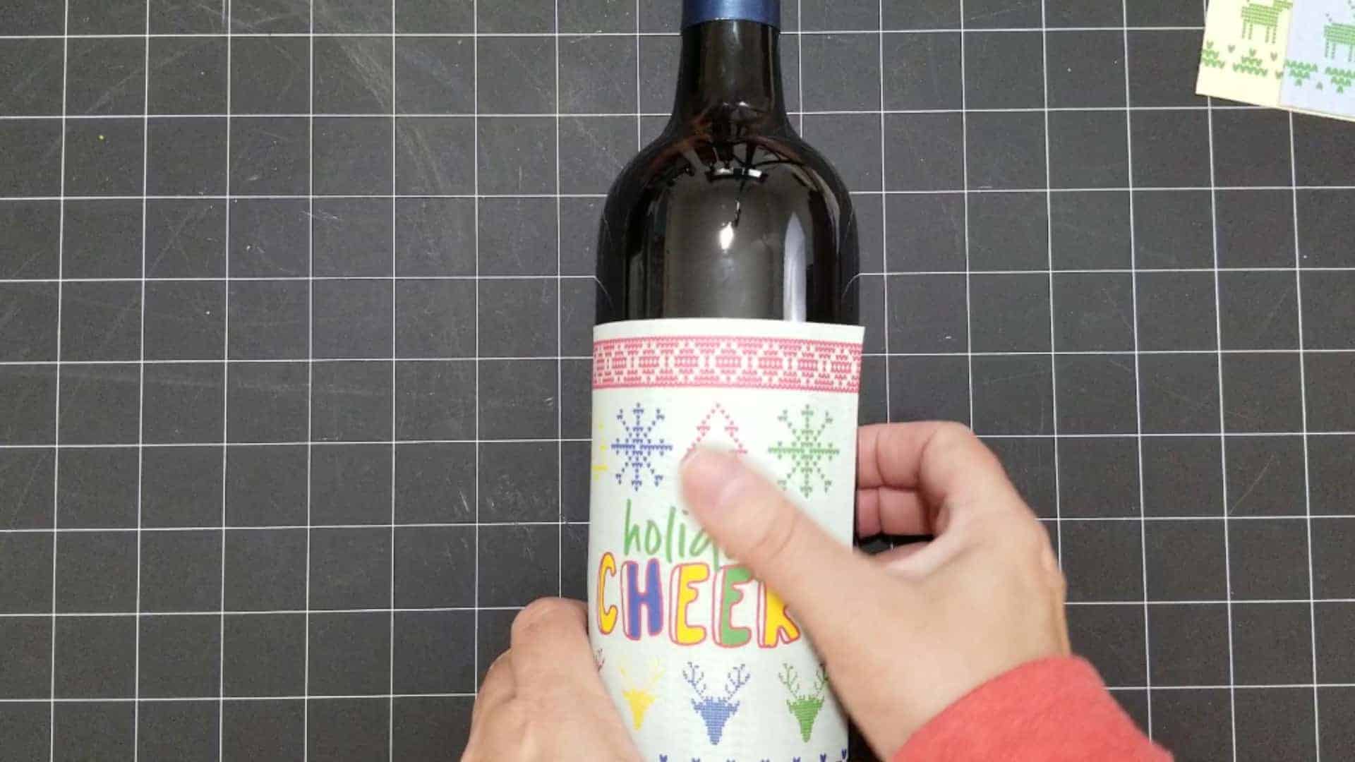 Smooth down the holiday wine label when it is stuck onto the bottle.