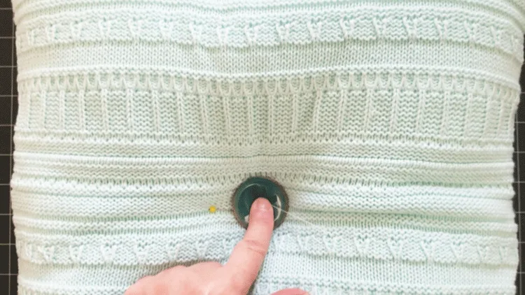Adding a large teal button to the center of a square sweater pillow