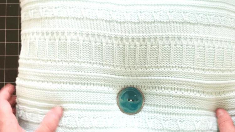 Adding a large teal button to the center of a square sweater pillow