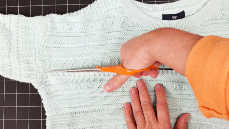 Cutting a sweater to make a cozy sweater pillow.