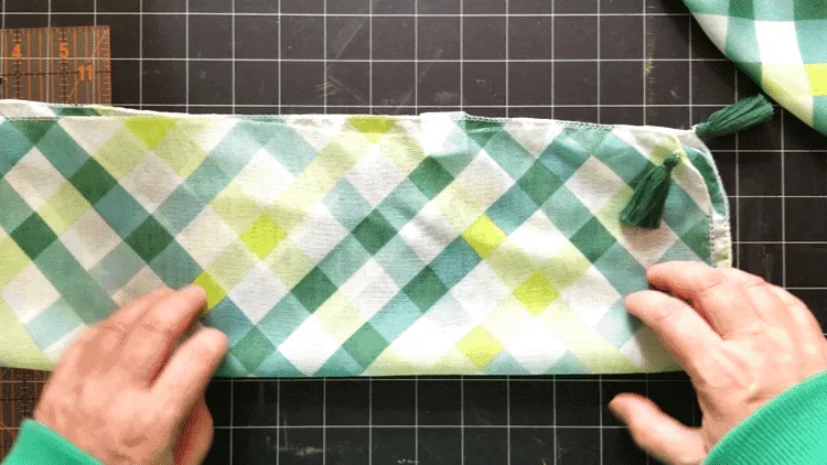 Folding a second scarf lengthwise to create a strap for the bag.
