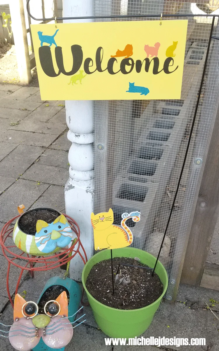 A custom welcome sign with script text and several cats.