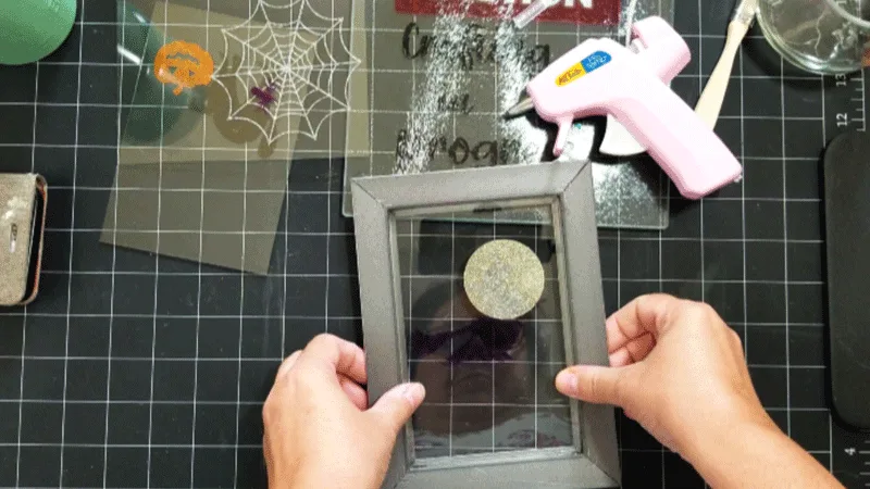 Using hot glue to attach the glass into the picture frames