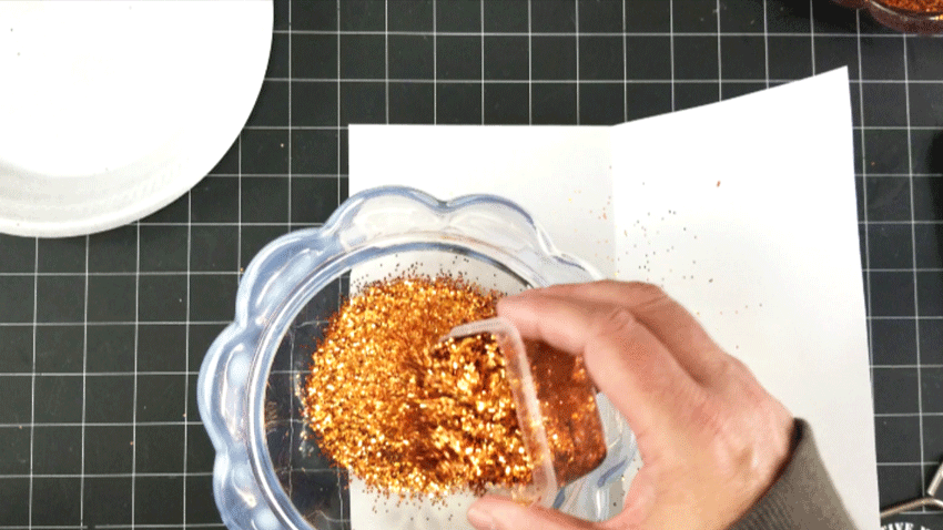 Adding the orange and gold glitter mixture to the pumpkin