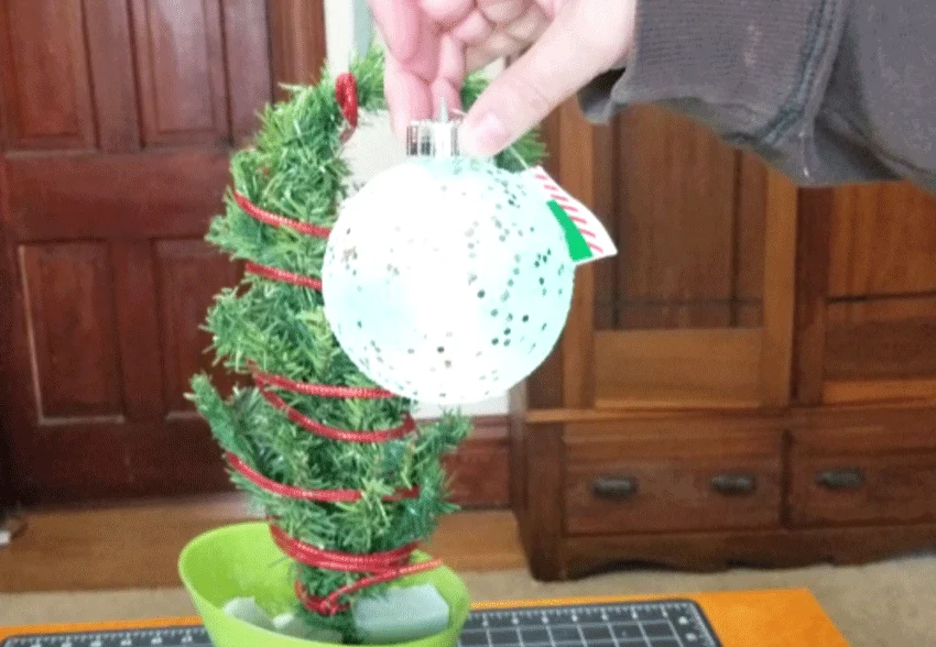 Adding the large light up ornament to the end of the curved branch.