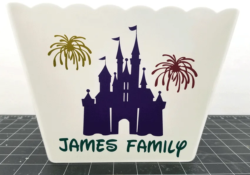 Side of popcorn bucket with Disney castle and James Family in vinyl