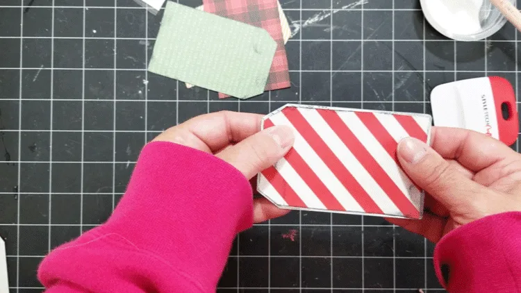 Adding the Christmas paper to the tag with the Mod Podge.